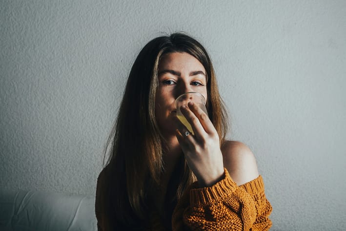 Frau sitzt entspannt zu Hause und trinkt achtsam einen Tee.